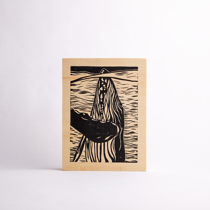 Linocut print on wood panel of a whale illustration